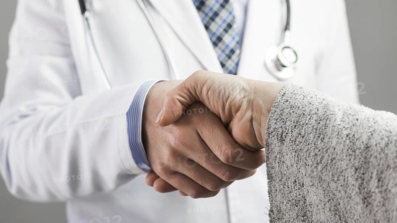 Close up male doctor patient shaking hands