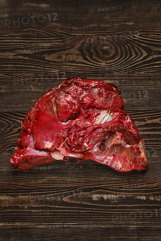 Overhead view of raw deer boneless ham over wooden background