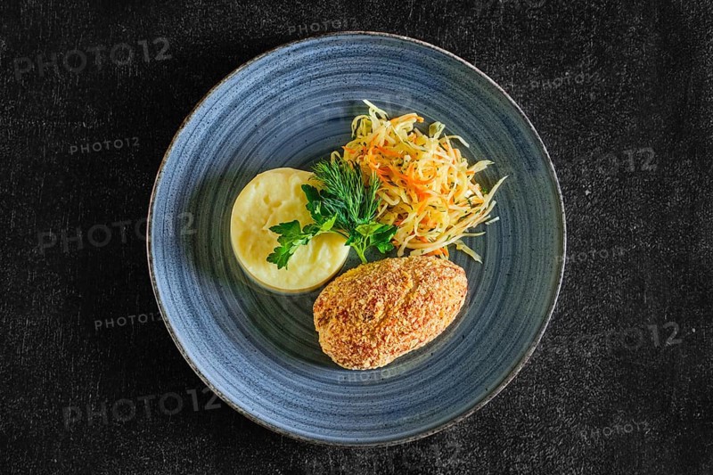 Top view of Kiev cutlet with mashed potato and pickled cabbage