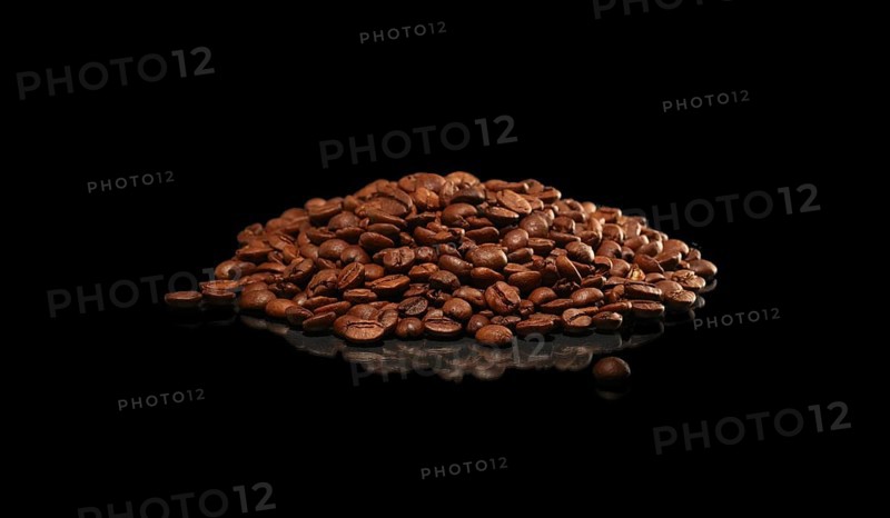 Roasted coffee beans scattered on dark glossy surface