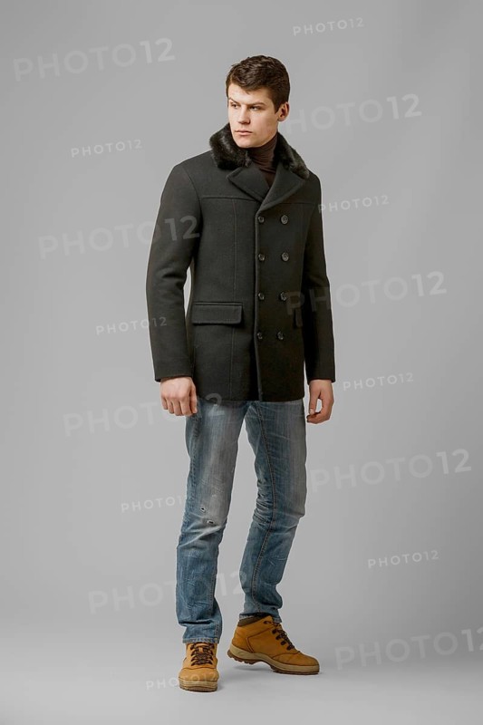Full length portrait of handsome man in warm woolen coat posing in studio