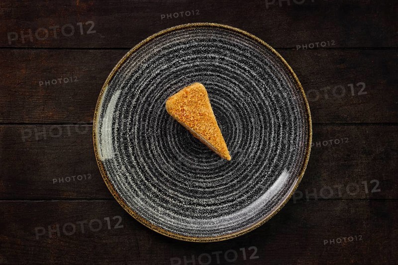 Top view of plate with piece of honey cake on wooden background