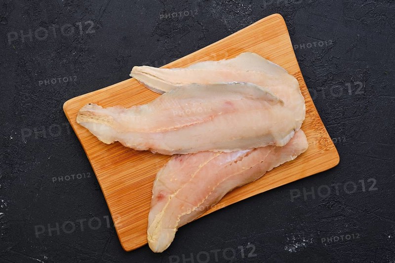 Top view of raw fresh haddock fillet on wooden cutting board