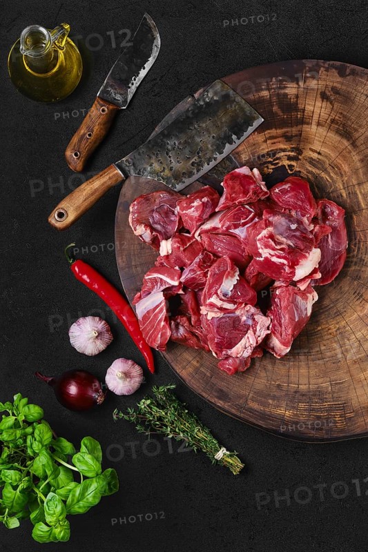 Overhead view of chopping fresh beef meat for goulash or stew on wooden chopping stump