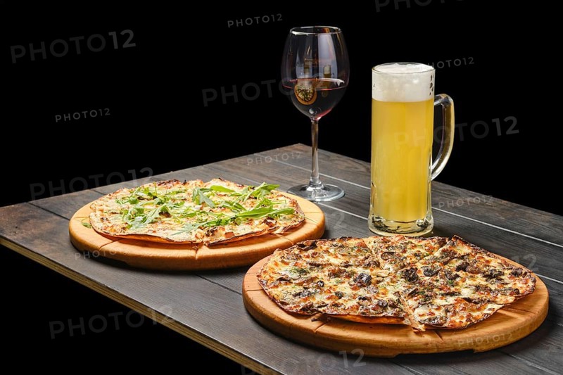 Two pizzas and a glass of lager beer and red wine on a table