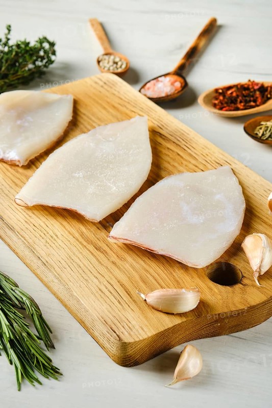 Raw frozen squid fillet on wooden cutting board