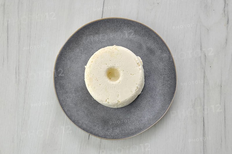 Top view of pressed cottage curd cheese on ceramic plate