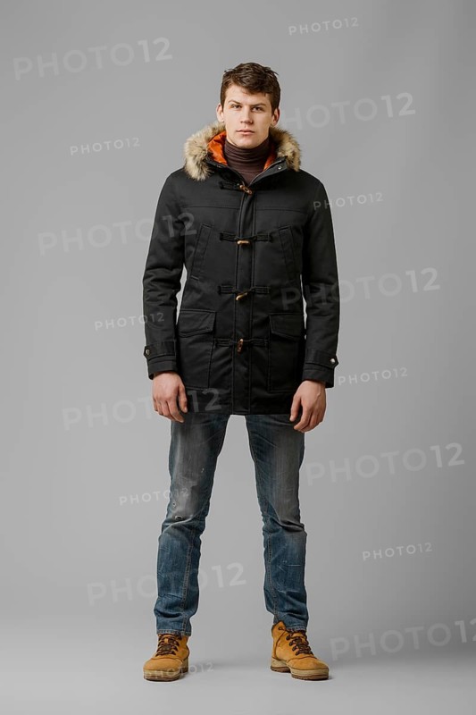 Full length portrait of handsome man in warm winter coat posing in studio