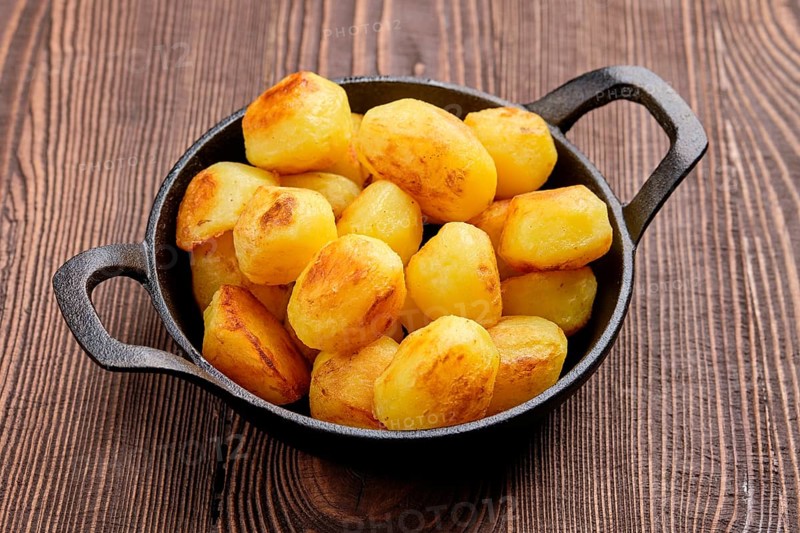 Baked potato in cast iron skillet on natural wooden background