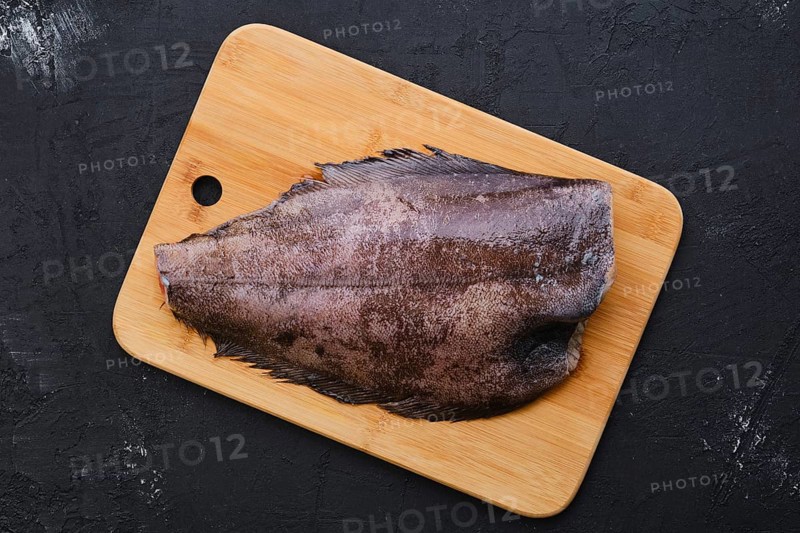 Top view of raw fresh halibut without head on wooden cutting board