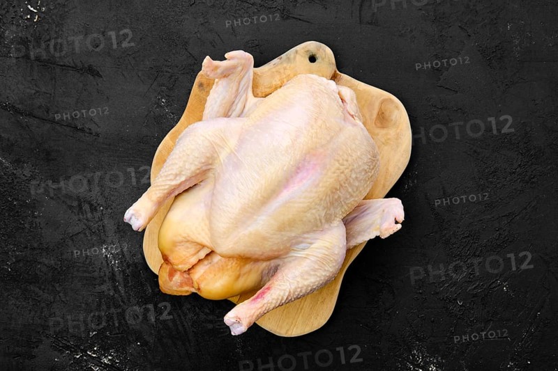 Fresh raw whole farm chicken on wooden cutting board