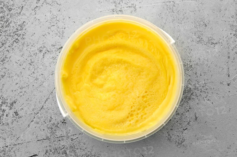Top view of homemade cream cheese in plastic bowl