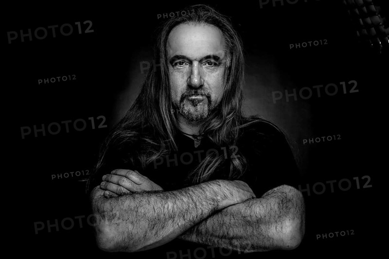 Man with long hair and hand with folded arms