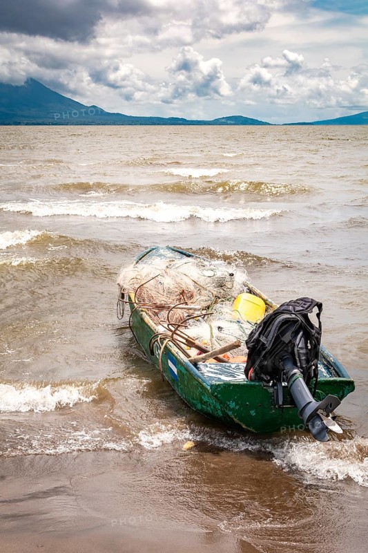 A fishing boat on the shore of a lake with volcanoes in the background. A fishing boat on a lake in Nicaragua. Concept of fishing boats parked at the seaside