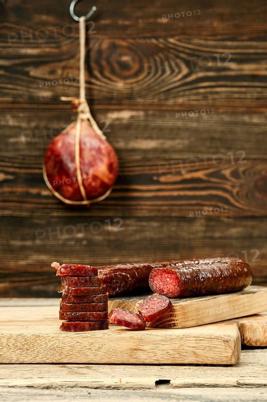 Smoked dried deer sausage cut on slices on wooden cutting board