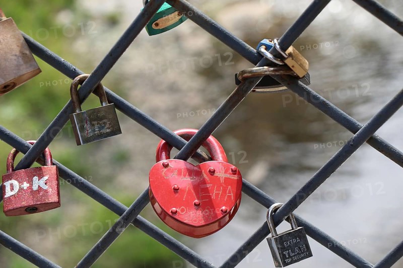 Many colorful metal love padlocks on fence