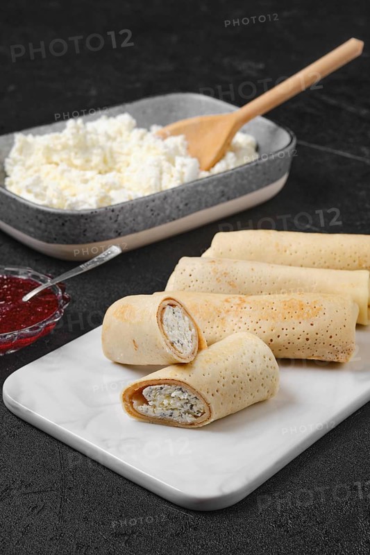Homemade pancakes stuffed with cottage cheese on marble serving plate