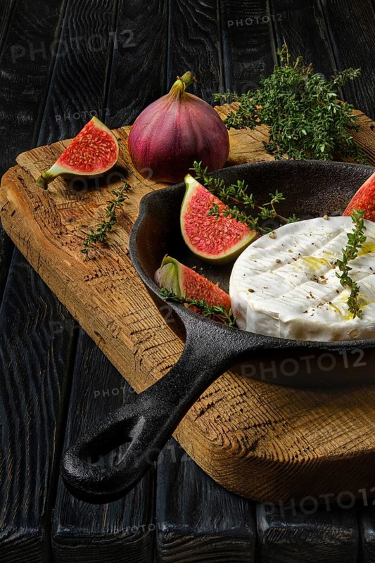 Closeup view of camembert cheese and figs ready for baking on frying pan