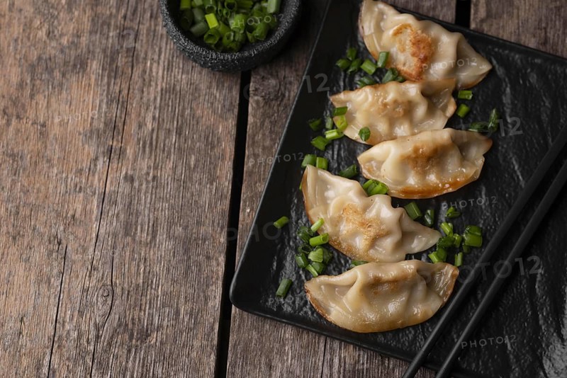 Flat lay of asian dumplings dish with herbs and copy space