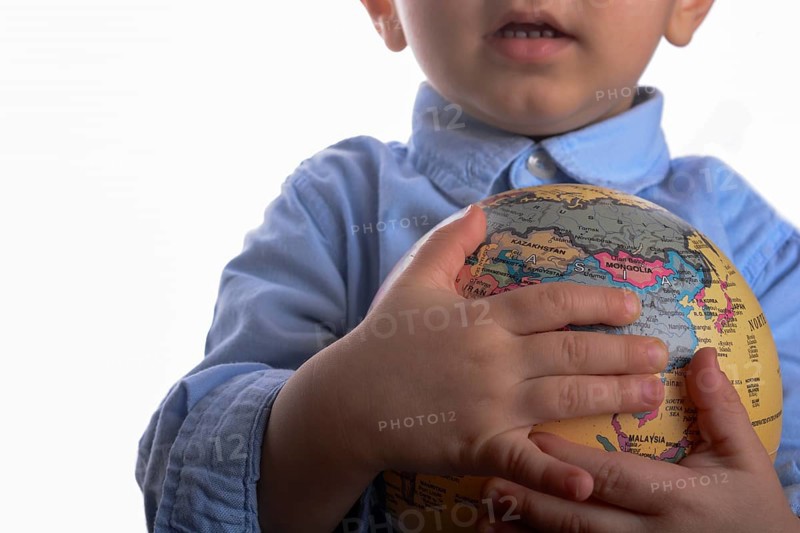Baby with blue shirt holding a globe in hand on white background