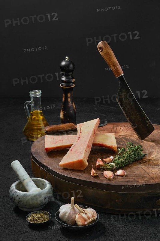 Large beef bone marrow chopped on half with spice on wooden stump
