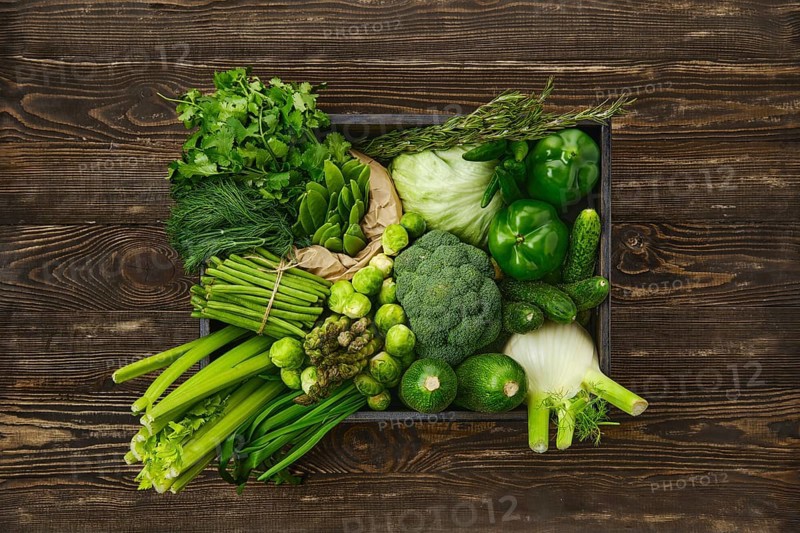 Various fresh green vegetables in wooden box on timber background