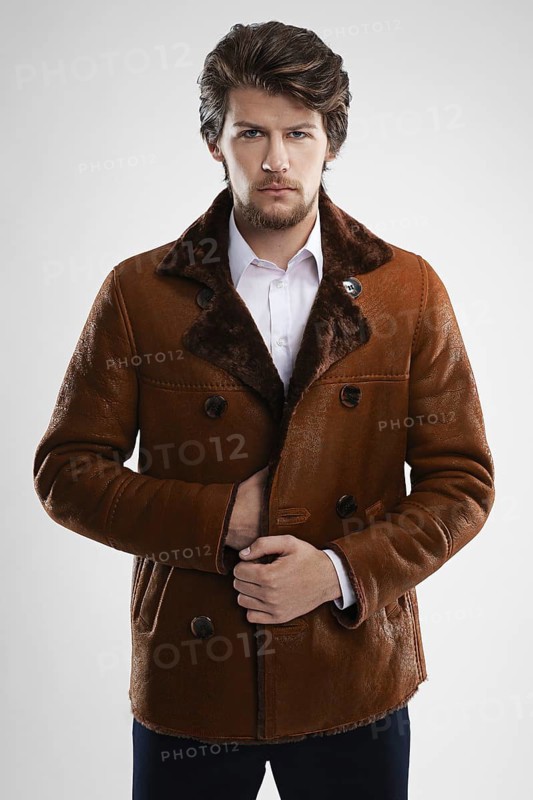 Brutal handsome unshaven man with beard and moustache in sheepskin coat with fur collar