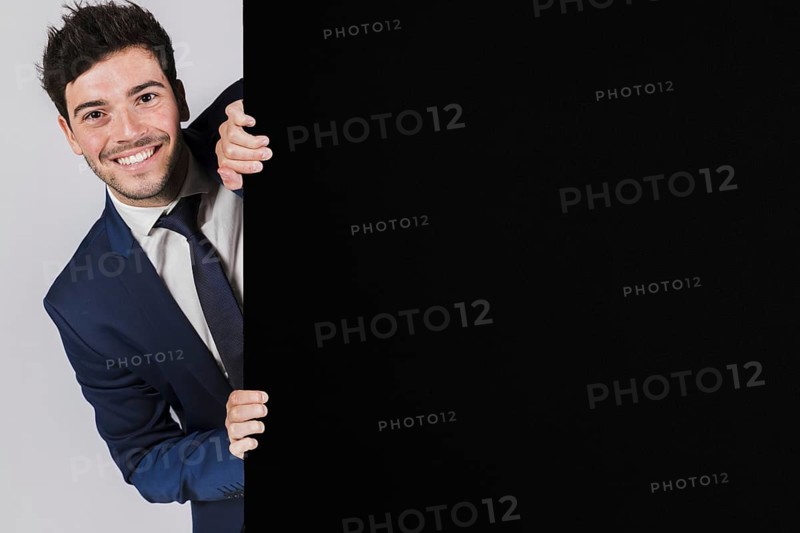 Smiling young businessman peeking from black placard. Resolution and high quality beautiful photo