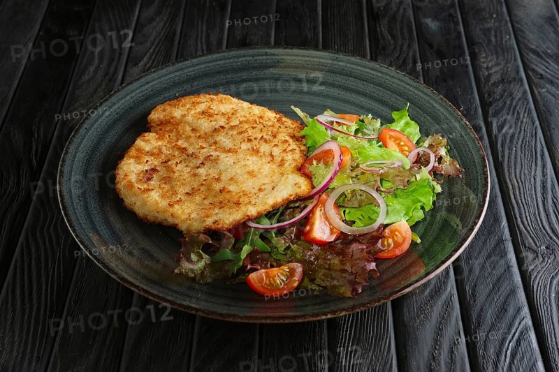 Schnitzel in breading with fresh vegetables and rings of red onion