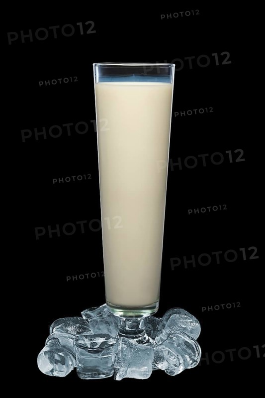 Tall glass of milk surrounded with ice cubes isolated on black background