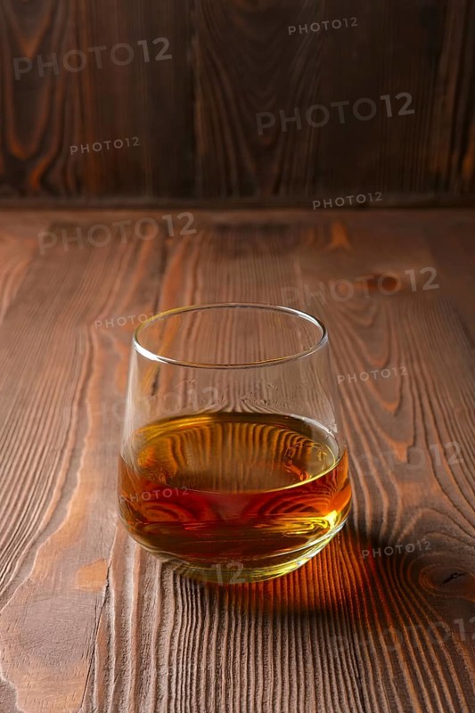 Snifter glass with pure whiskey on wooden table