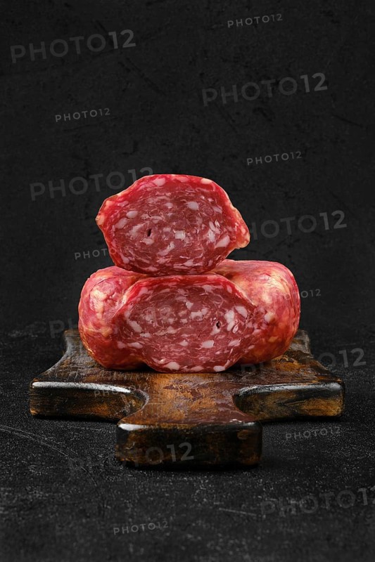Closeup view of smoked beef sausage on cutting board over black background