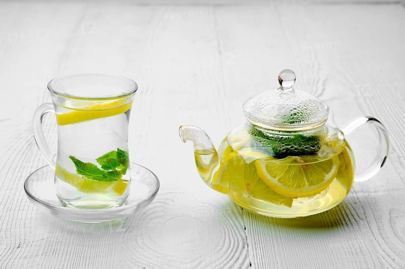 Antioxidant hot drink with lemon and mint in transparent tea pot and glass