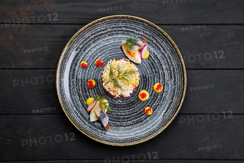 Top view of herring layered salad decorated with a quarter of a boiled egg and a piece of herring
