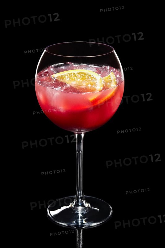 Cold lemon cocktail with a sparkling wine and raspberries with ice in wine glass isolated on black