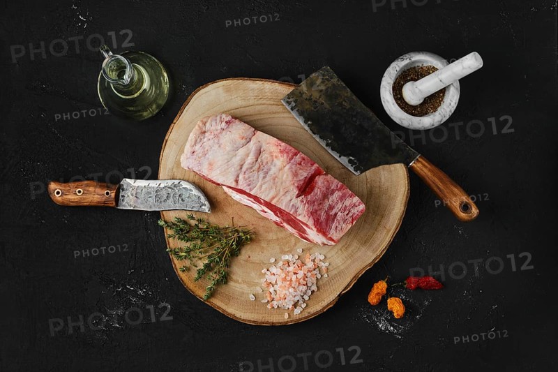 Overhead view of raw beef brisket on wooden cutting board