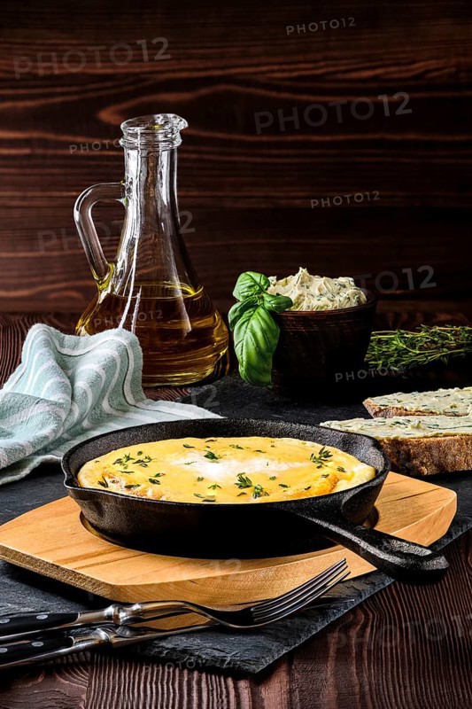 Omelette in cast iron skillet with bread and herbal butter