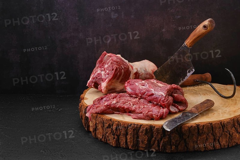 Pieces of fresh lamb neck on cutting stump in slaughterhouse
