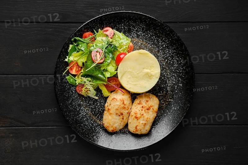 Top view of meat cutlet with mashed potato and fresh vegetables on a plate