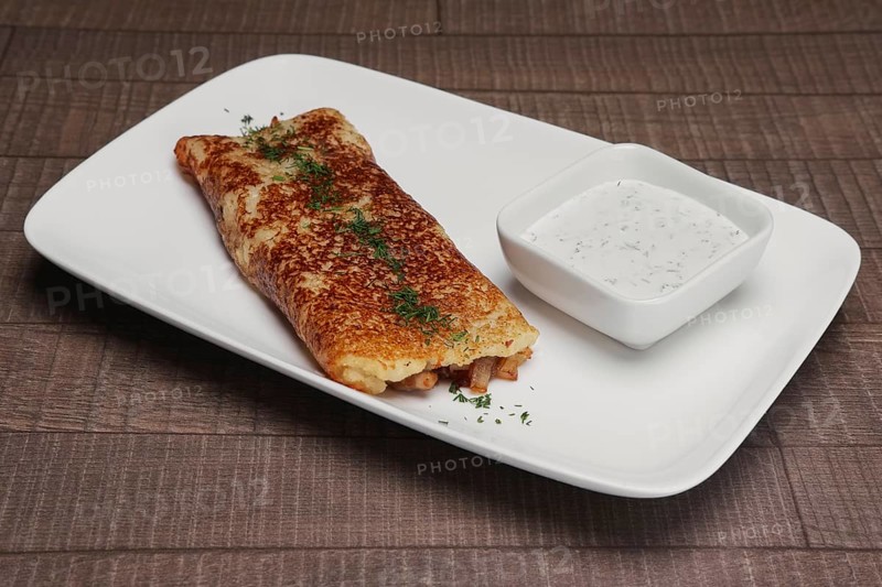 Traditional russian pancake with ham and sauce