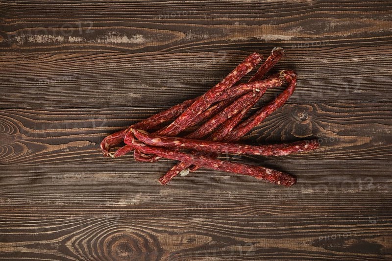 Overhead view of air dried deer and pork sausage on wooden background