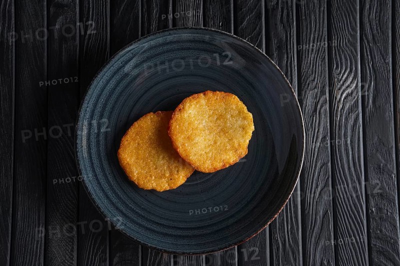 Portion of fried potato pancakes on dark wooden table