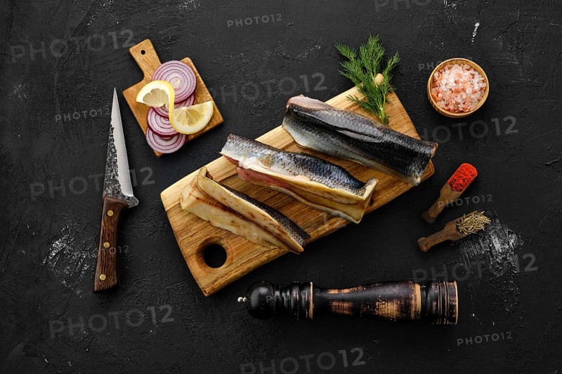 Raw fresh frozen herring carcass with spices on cutting board