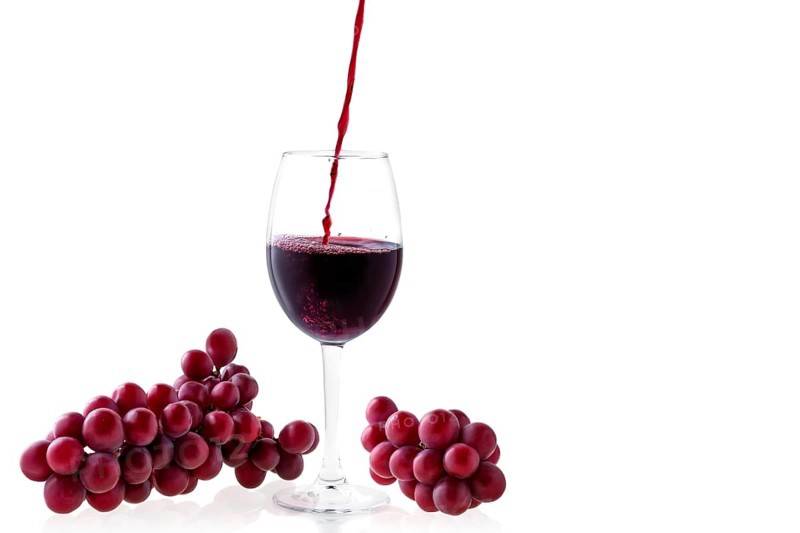 Pouring red wine in glass isolated on white background