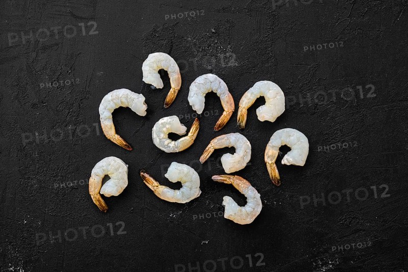 Peeled fresh raw white prawns on wooden background
