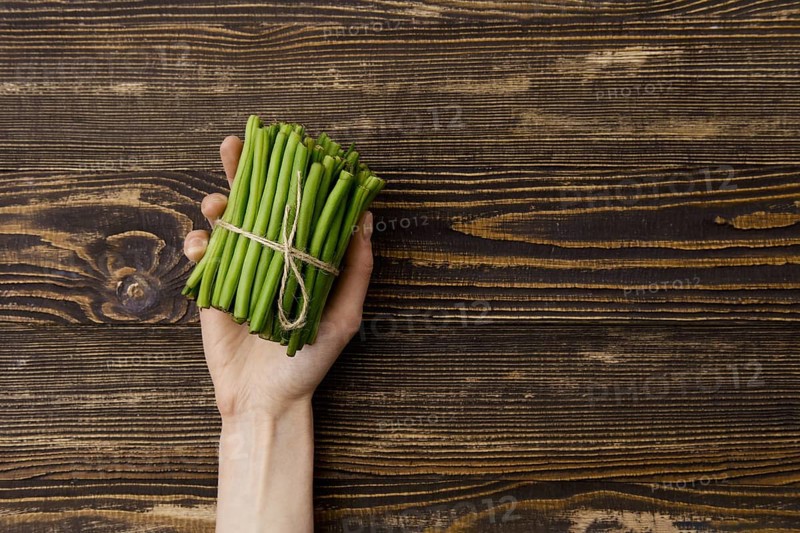 Overhead view of fresh green beans in hand over wooden background