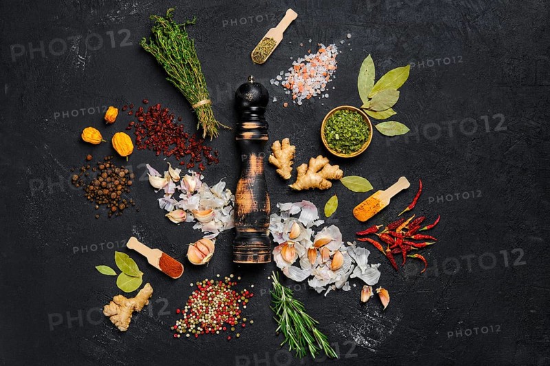 Assortment of spice and seasonings scattered on dark background