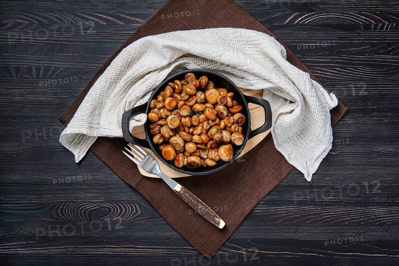 Overhead view of cast iron skillet with fried champignon with spice