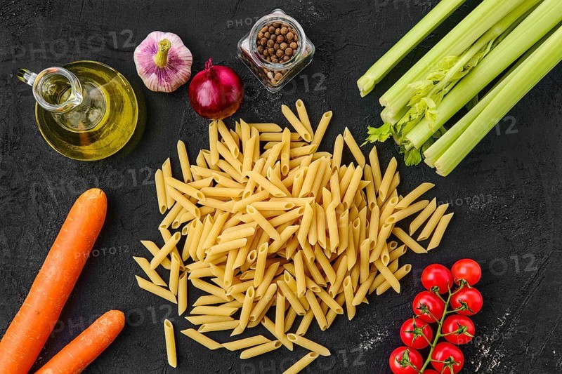 Top view of penne pasta with spice and herbs on black background