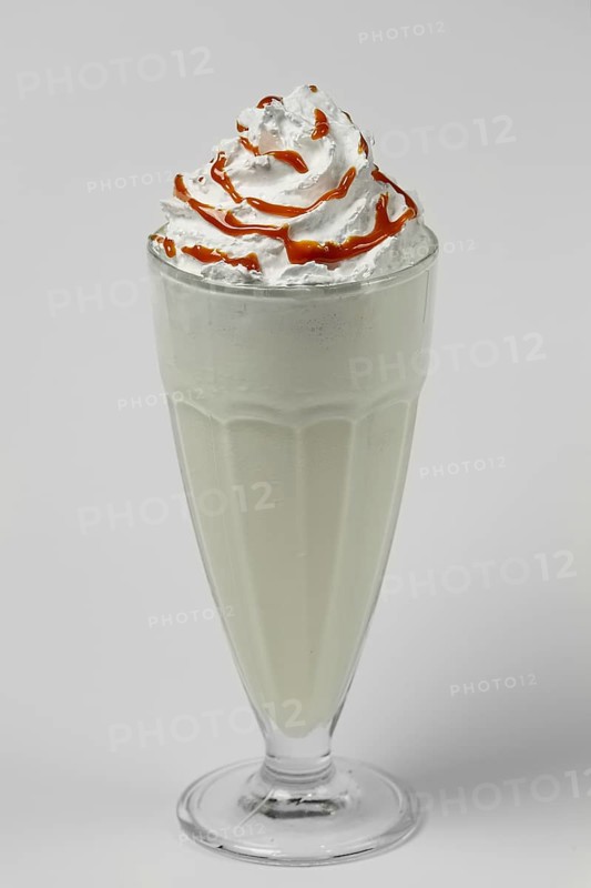 Melon and caramel milkshake summer cocktail in tall facetted glass on gray background